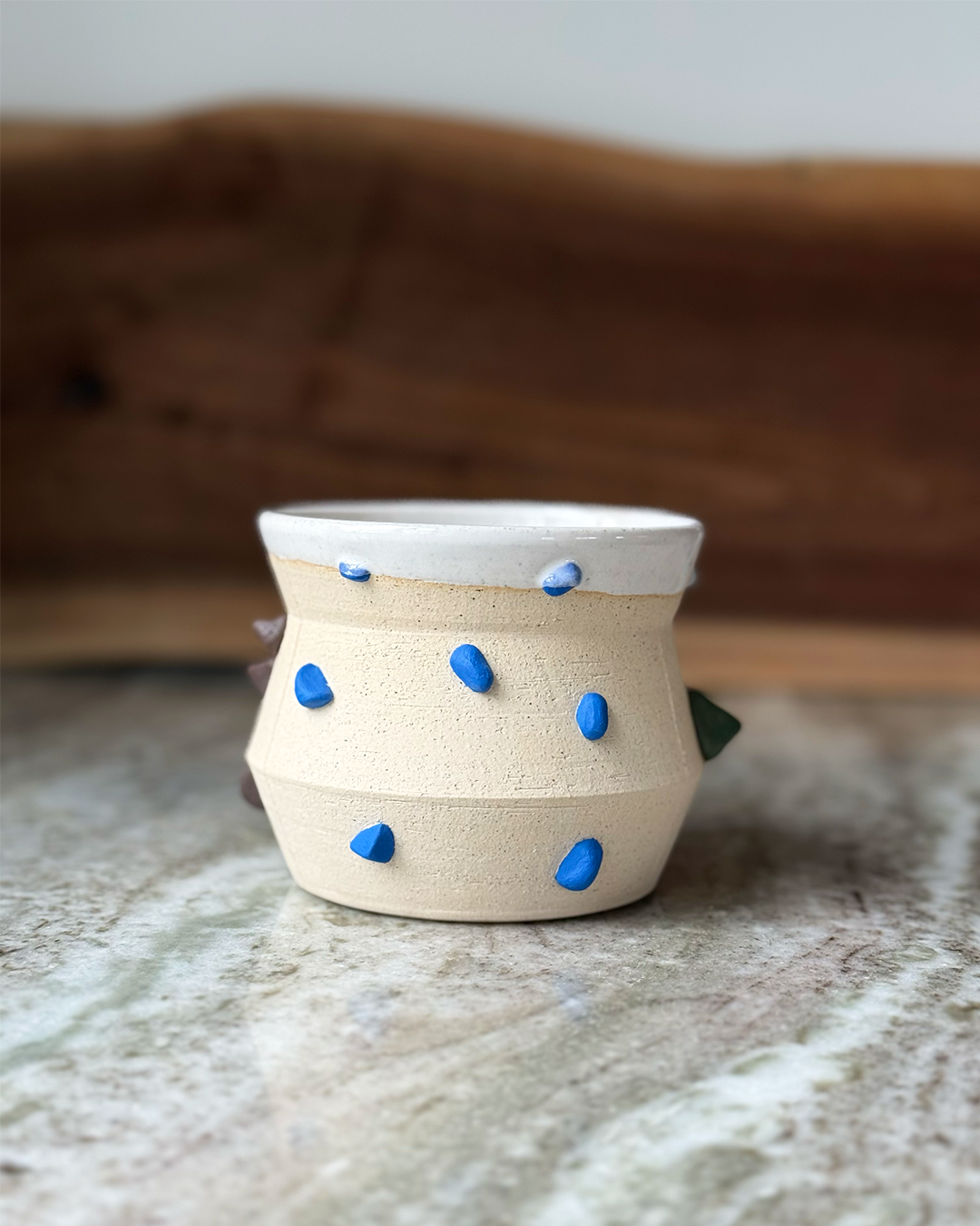 Mug inspired by climbing wall with sculpted handholds in different colors a marble and wood backdrop