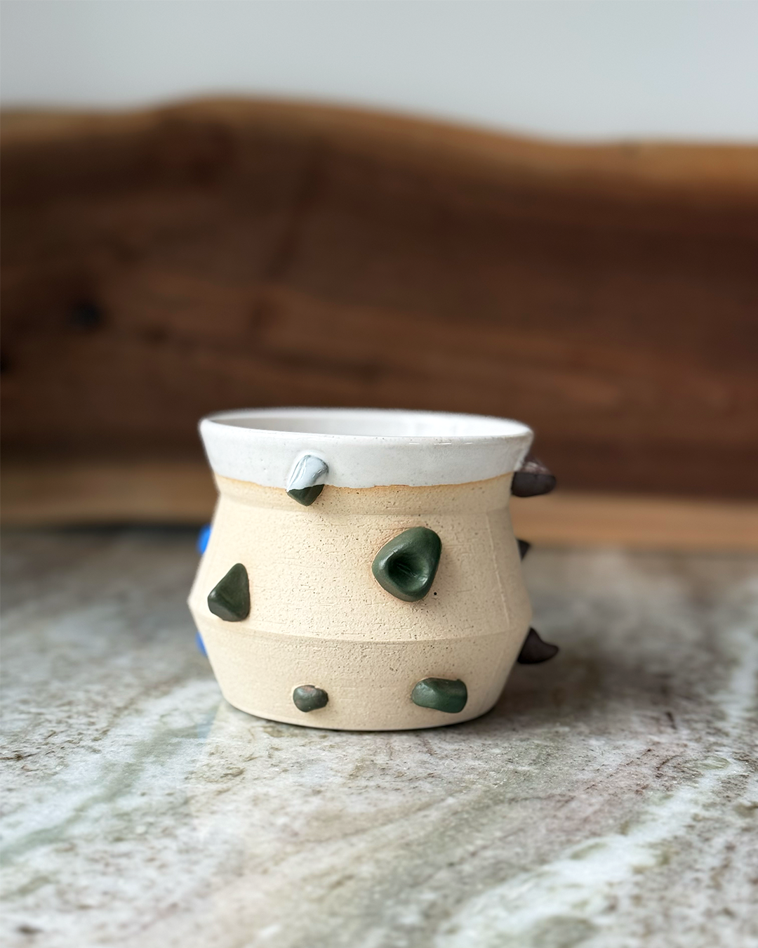Mug inspired by climbing wall with sculpted handholds in different colors a marble and wood backdrop
