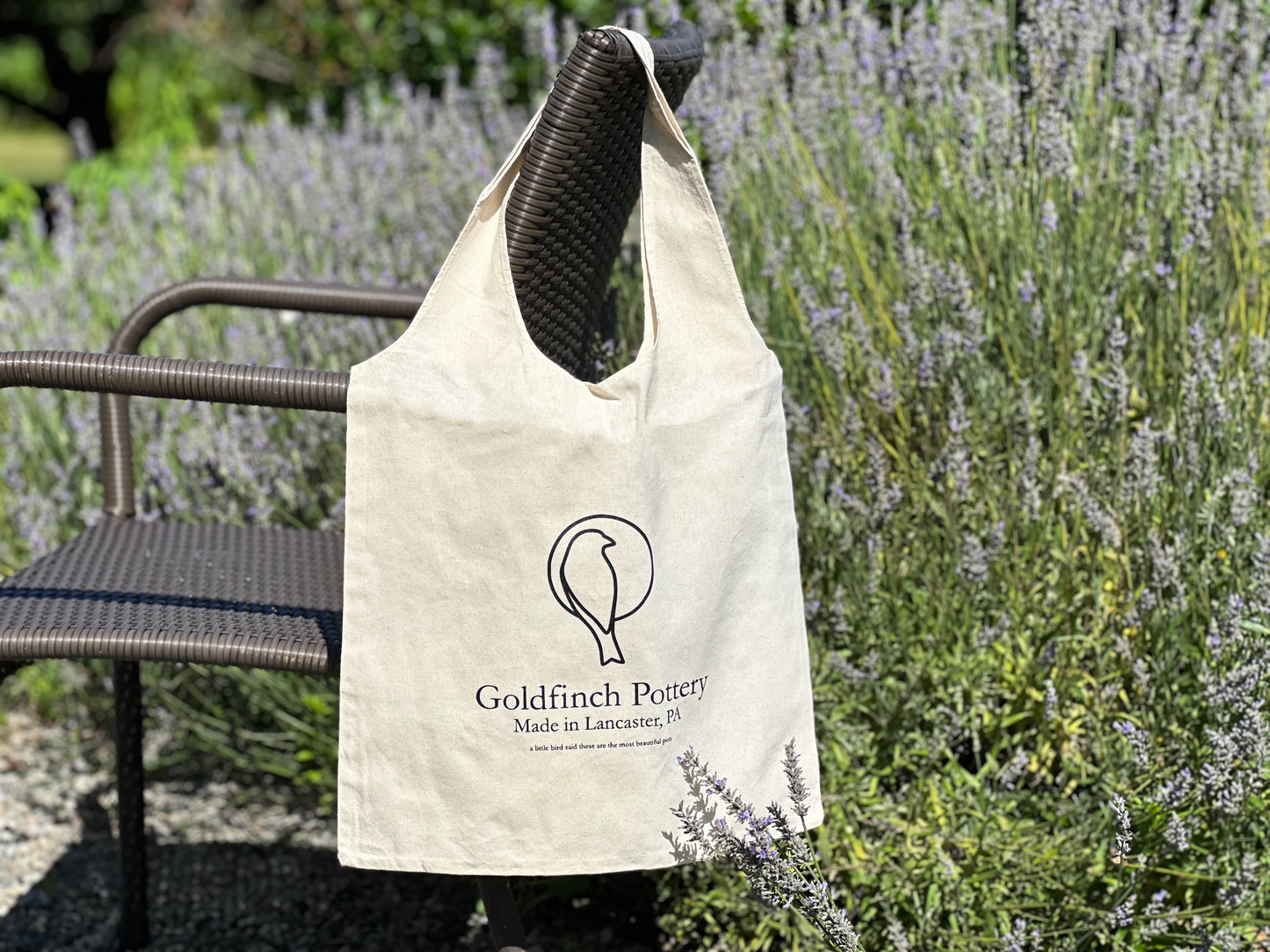 Canvas bag in a lavendar patch outside on the arm of a chair