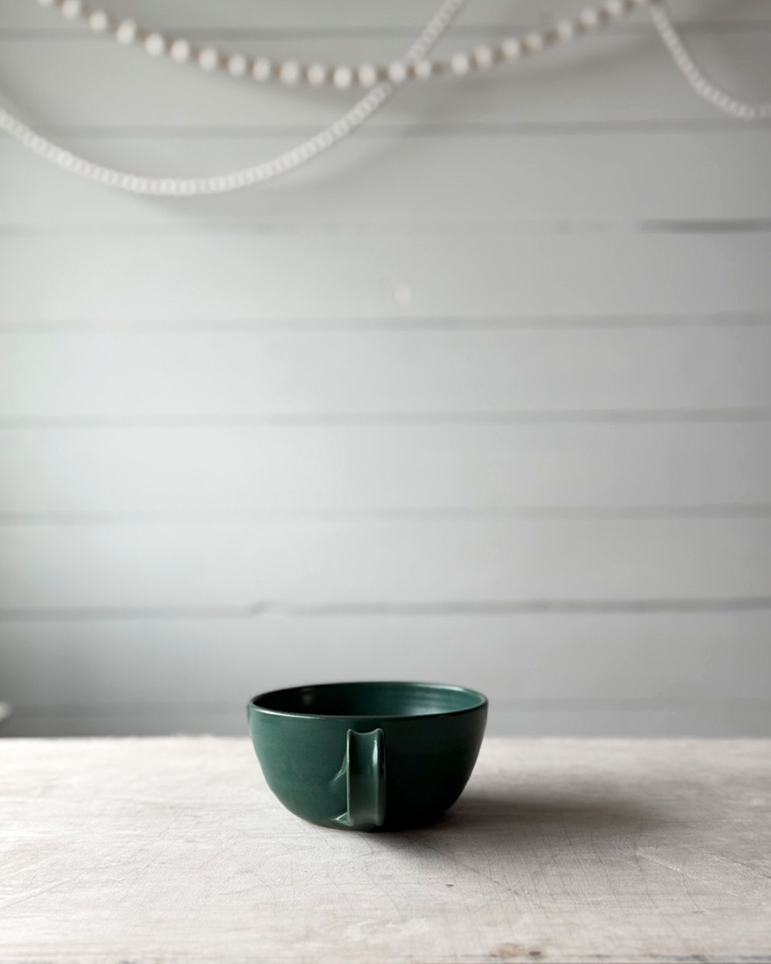 Green ceramic cup on a wooden surface with a neutral background