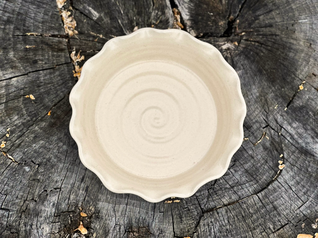 linen colored pie dish resting on a tree stump