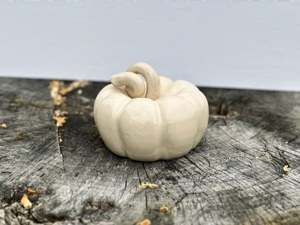 one medium linen pumpkin resting on a tree stump side view