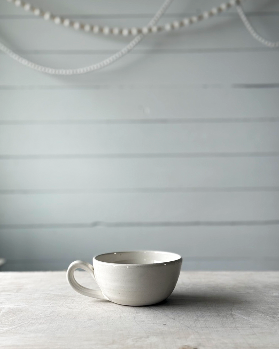 White ceramic cup on a textured surface with a light gray background
