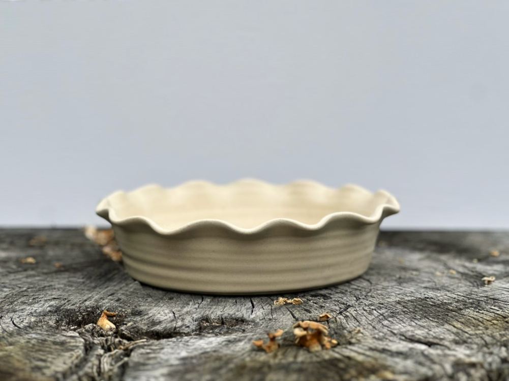 Linen pie dish resting on a tree stump with a white backdrop