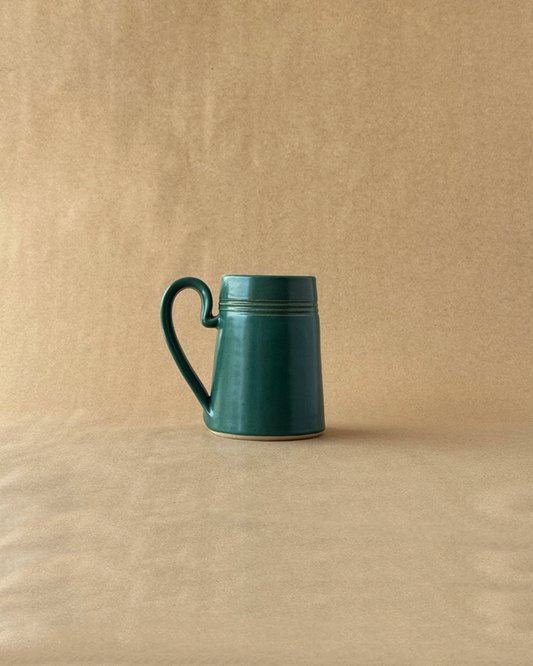 Green ceramic mug on a beige background