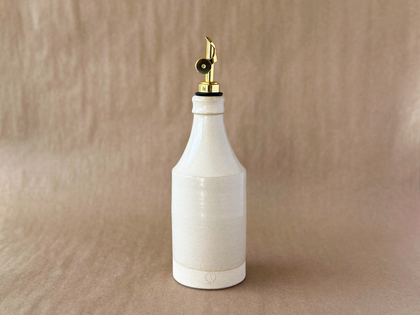 Brown Backdrop with a Handmade Ceramic Oil Bottle with a Gold weighted oil pour spout